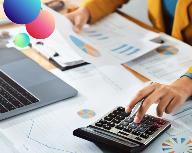 Manos trabajando con unos gráficos, una calculadora y un ordenador portátil