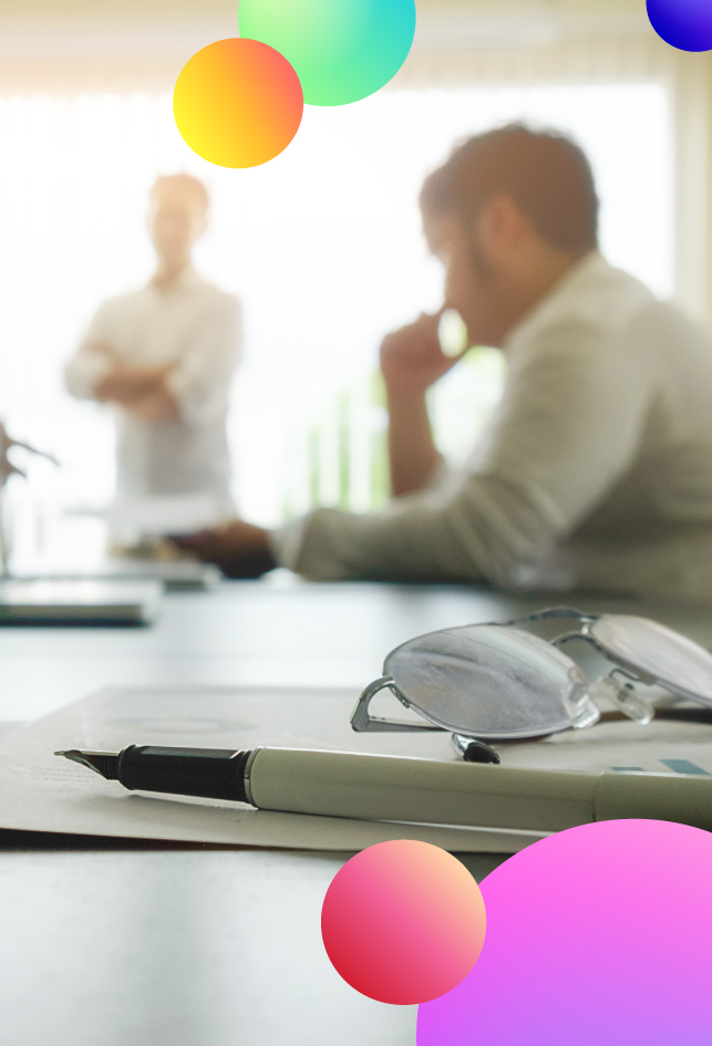Pluma, papel y gafas con dos trabajadores al fondo